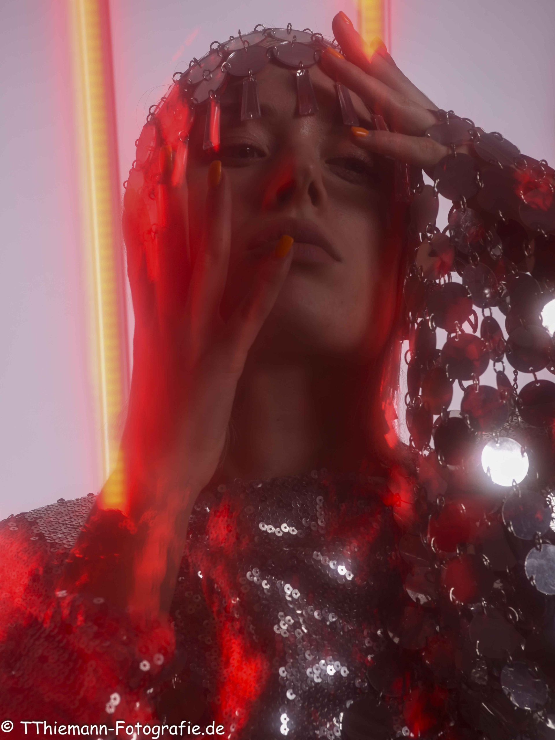 Portraits Fotografie Modell Marie-Denise mit Pailletten in rotem Licht