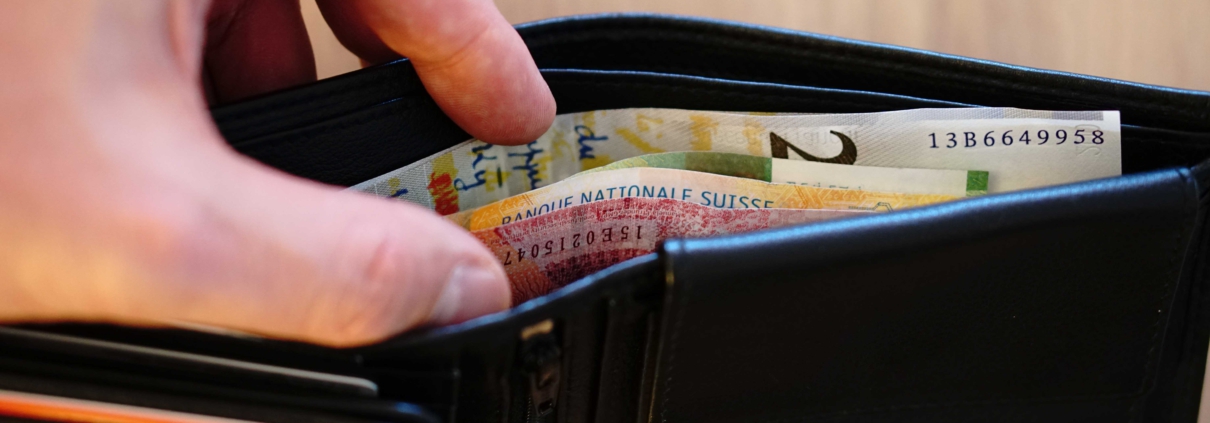 Brieftasche mit Geldscheinen und einer Hand die reingreift