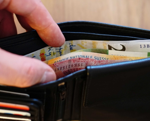 Brieftasche mit Geldscheinen und einer Hand die reingreift