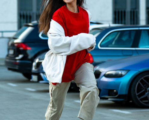 Modeaufnahmen einer jungen, asiatisch wirkenden Frau mit rotem Shirt und langen dunklen Haaren, welche auf mich zu rennt.