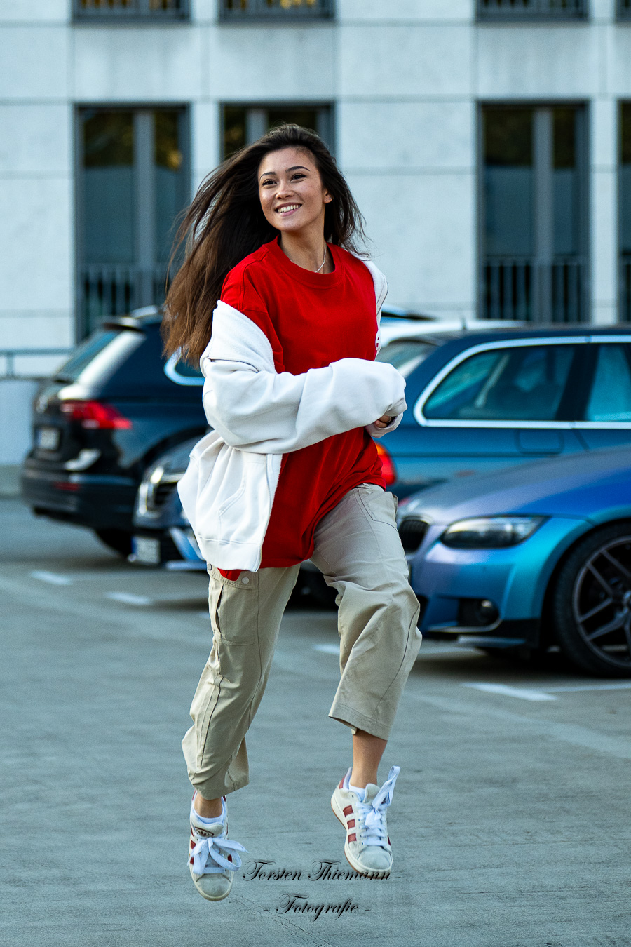 Modeaufnahmen einer jungen, asiatisch wirkenden Frau mit rotem Shirt und langen dunklen Haaren, welche auf mich zu rennt.